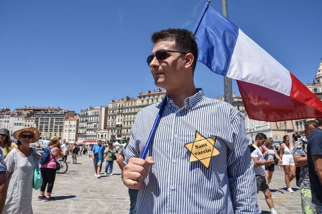 July 17, 2021, Marseille, France: Protester holds a French flag and flaunts a Jewish yellow star on his chest during the demonstration against the health pass in Marseille..More than 4,000 people in Marseille demonstrated against a health pass that French President Emmanuel Macron announced among the new anti-Covid 19 measures which will be necessary to be frequenting cafÃ terraces, restaurants, cinemas, theatres and other culture and leisure activities to help contain the spread of the Covid-19 virus. Marseille France - ZUMAs197 20210717_zaa_s197_446 Copyright: xGerardxBottinox