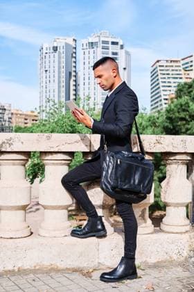IMAGO Creative: Kreative Renaissance -- der junge Entrepreneur Side view of focused young Hispanic male executive manager in classy suit with bag reading information on tablet while standing near railing on urban terrace, Model released AdalbertoRodriguez_Businessman_3.jpg Copyright: xAdalbertoxRodriguezx MR
