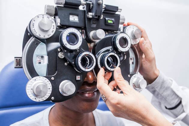 Optometrist adjusting the optometry equipment during study of the eyesight of a black woman, Model released DavidFuentes_Optometry_23.jpg Copyright: xDavidxFuentesx MR