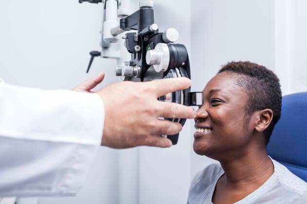 Optometrist adjusting the optometry equipment during study of the eyesight of a happy black woman, Model released DavidFuentes_Optometry_5.jpg Copyright: xDavidxFuentesx MR