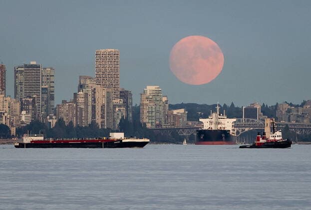 July 22, 2021, Vancouver, BC, Canada: A nearly full moon rises behind condo towers in the downtown skyline as a tugboat pulls a barge and a bulk carrier cargo ship sits at anchor on English Bay, in Vancouver, on Thursday, July 22, 2021. Vancouver Canada  - ZUMAc35_ 20210722_zaf_c35_042 Copyright: xDarrylxDyckx