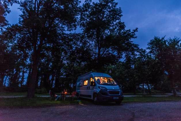 IMAGO Creative: Herbst, Touren mit dem Camper Camper sitzen zur blauen Stunde an einem lauen Sommerabend vor ihrem Camper auf Campingstühlen. Baden Württemberg, Deutschland. Mit einem Campervan unterwegs *** Campers sitting on camping chairs in front of their camper at blue hour on a warm summer evening Baden Württemberg, Germany On the road with a campervan