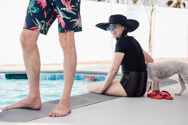 Happy woman with dog sitting behind man at poolside during vacation model released Symbolfoto property released ACTF00111