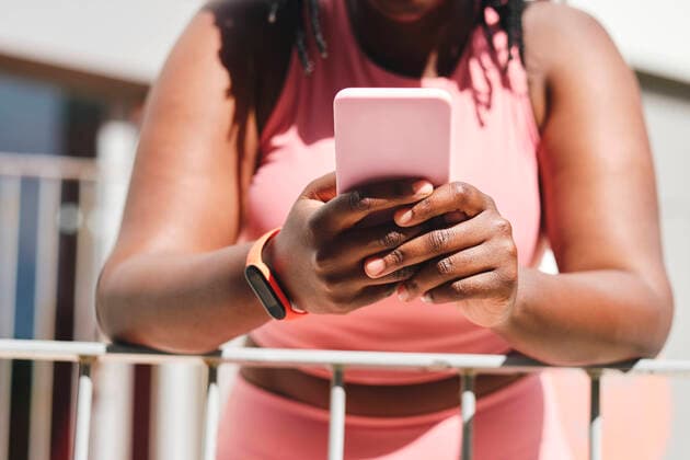 IMAGO Creative: Clickbait, Sport und Fitness Young woman using mobile phone while leaning on railing model released Symbolfoto AODF00541