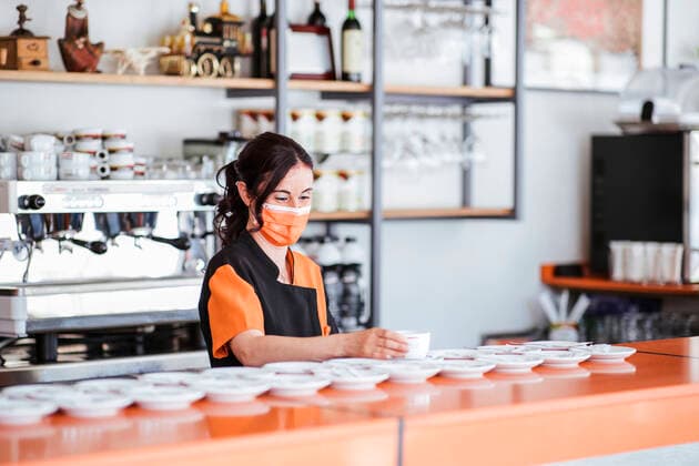 Waitress wearing protective face mask arranging cup on saucer at cafeteria counter model released Symbolfoto property released LJF02222