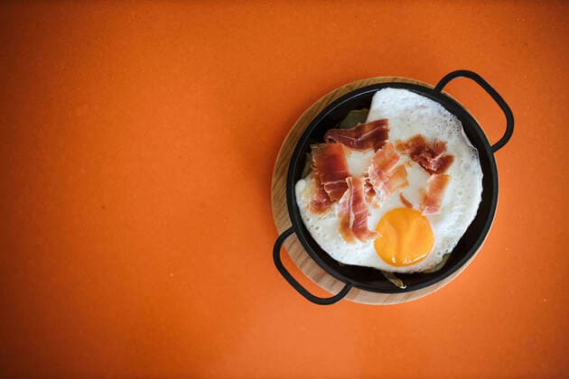 Fried egg with ham in pan on orange table at cafeteria property released LJF02228