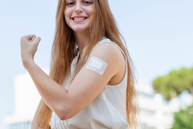Smiling redhead businesswoman flexing muscles after taking vaccine during pandemic model released Symbolfoto EIF01489