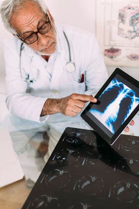 Senior male doctor explaining digital x-ray image on tablet in hospital model released Symbolfoto property released EGHF00041