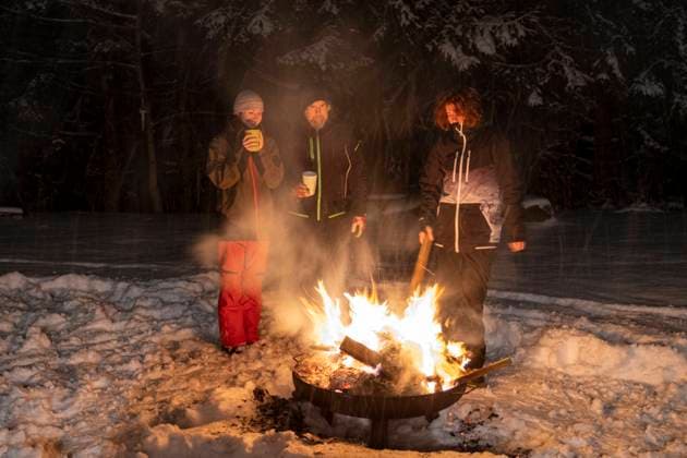 Family standing together around campfire during winter at night model released Symbolfoto LBF03532