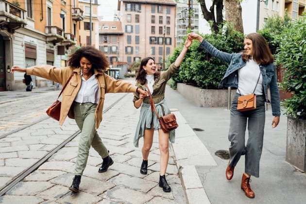 IMAGO Creative: Gesellschaft, Integration Cheerful women holding hands while walking at city street model released Symbolfoto MEUF03496