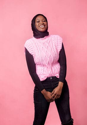 Smiling young woman standing in front of pink background model released Symbolfoto MGOF04731