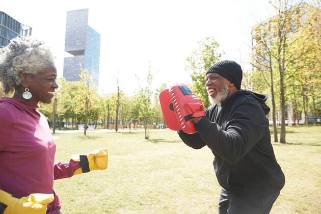 IMAGO Creative: Sport in der Stadt Smiling woman practicing boxing with man at park model released Symbolfoto PMF01985
