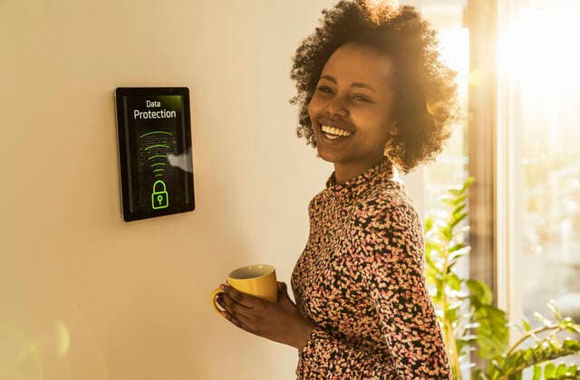 Cheerful woman with coffee cup standing by home automation device model released Symbolfoto property released UUF23544