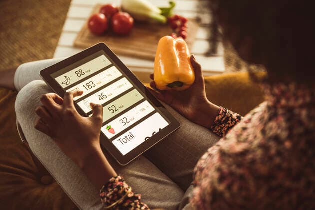 Woman planning diet through digital tablet at home model released Symbolfoto property released UUF23559