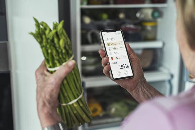 Woman calculating food calories through smart phone at home model released Symbolfoto property released UUF23659