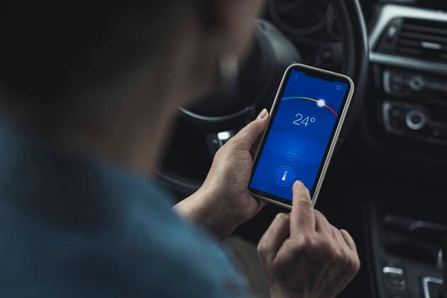 IMAGO Creative: Corporate: Klimaschutz, Digitalisierung und Urbanisierung Woman operating temperature through smart phone in car model released Symbolfoto property released UUF23727