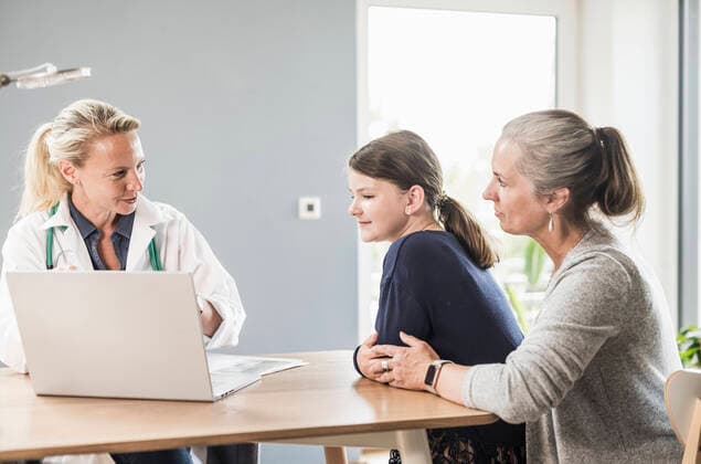 IMAGO Creative: Internationaler Frauentag, Mental Load und Care-Arbeit Pediatrician explaining patient and woman with laptop at doctor s office model released Symbolfoto property released UUF23903