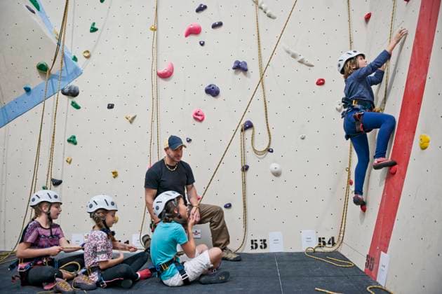 IMAGO Creative: Lokalhelden - Jugendsportbildung climbing coach assisting group of girls at indoor climbing wall London, England, United Kingdom CR_THHE210715-797604-01 ,model released, Symbolfoto