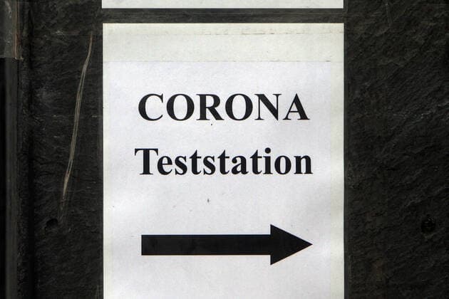Zettel mit Aufschrift Corona Teststation mit Richtungspfeil klebt an einer Hauswand in der Innenstadt von Düsseldorf, Nordrhein Westfalen, Deutschland