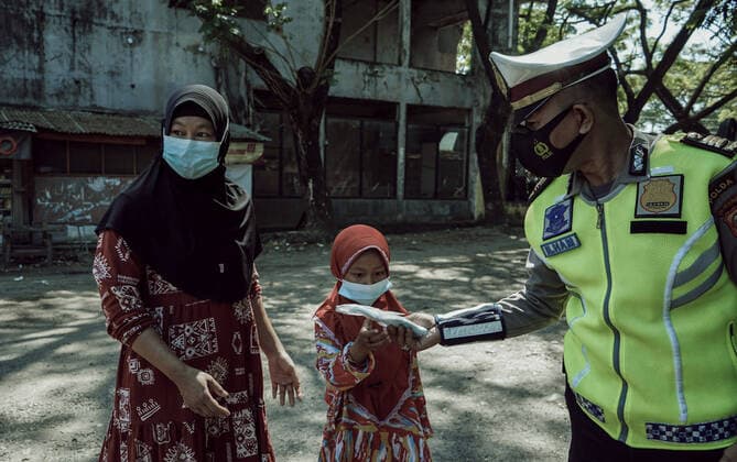 July 28, 2021, Makassar, South Sulawesi, Indonesia: A police officer gives a mask to prospective city transportation passengers at the Mallengkeri Terminal, Makassar, Indonesia. The health protocol campaign and health checks continue to be carried out by the police to prevent the spread of Covid-19 in Indonesia. Makassar Indonesia - ZUMAb223 20210728_zip_b223_003 Copyright: xHerwinxBaharx