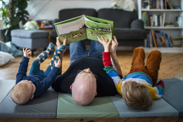 IMAGO Creative: Menschen in Berlin - Generationen Symbolfoto: Ein Vater liest mit seinen beiden Kindern auf dem Boden liegend ein Buch. Berlin, 02.02.2021. Berlin Deutschland *** Symbol photo A father reads a book with his two children lying on the floor Berlin, 02 02 2021 Berlin Germany Copyright: xJaninexSchmitz photothek.dex