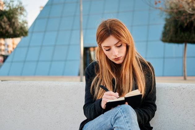 IMAGO Creative, Lifestyle, Tik Tok-Trend thatgirl Woman writes in her notebook with a commercial building at her back Villena, VC, Spain CR_CRBL210315B-679533-01 ,model released, Symbolfoto