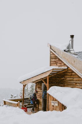 IMAGO Creative: Jahreszeit Winter, Spaziergang Two friends walk into a rustic cabin while it snows outside Winthrop, WA, United States CR_HYZV210212-372248-01