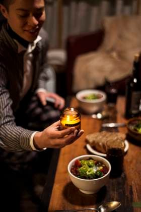 queer person smiles and places candle at dinner table at night Brandenburg, BB, Germany CR_PIDODS210315A-641075-01 ,model released, Symbolfoto