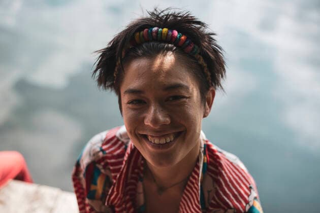 non-binary asian person smiles in colourful shirt by lake Garbicz, Lubusz Voivodeship, Poland CR_PIDODS210721-787643-01 ,model released, Symbolfoto