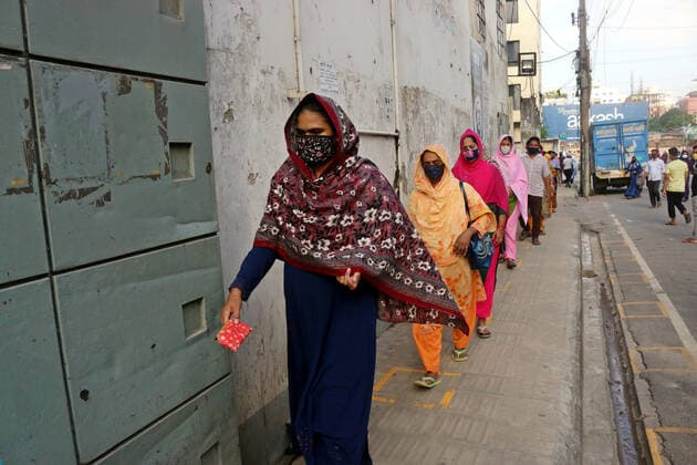 August 5, 2021 , Dhaka, Bangladesh: Security personal checks the body temperature of Garment workers before entering a Garment factory after garment factories reopened during Covid-19 lockdown in Dhaka. Dhaka Bangladesh  - ZUMAr336 20210805_int_r336_011 Copyright: xHabiburxRahmanx