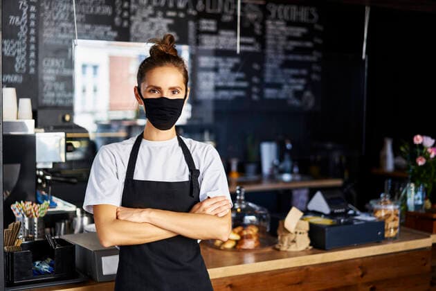 Portrait of waitress in protective face mask with arms crossed standing at cafe model released Symbolfoto property released BSZF01768