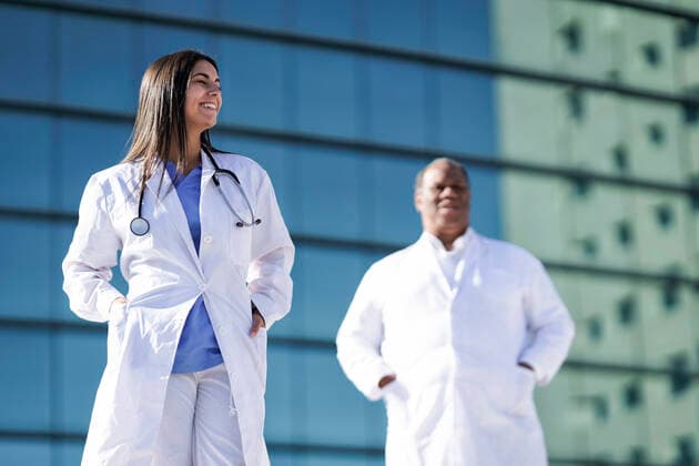 Confident doctors standing with hands in pockets against hospital model released Symbolfoto GGGF00035