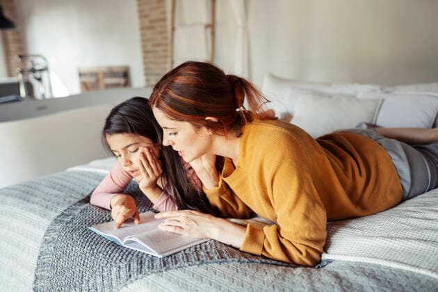 IMAGO Creative: Kulturelle Folgen der Pandemie: Gesundheitsbewußtsein und Alleinsein Mother and daughter reading book while lying on bed at home model released Symbolfoto property released JSMF01856
