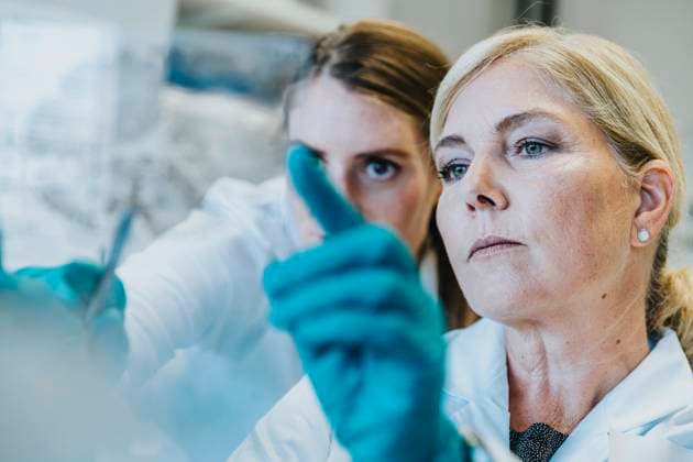 Scientist and assistant discussing while examining human brain microscope slide at laboratory model released Symbolfoto property released MFF06458