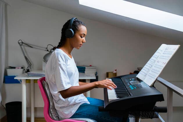 IMAGO Creative: Bildung, Musikerziehung Teenage girl playing piano while sitting at home model released Symbolfoto property released MGIF01029