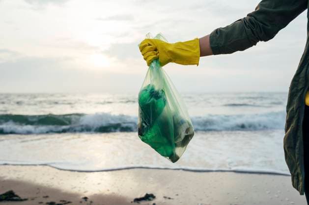 Creative Highlights Symbolbilder Mid adult woman holding garbage bag while standing at beach model released Symbolfoto OYF00248