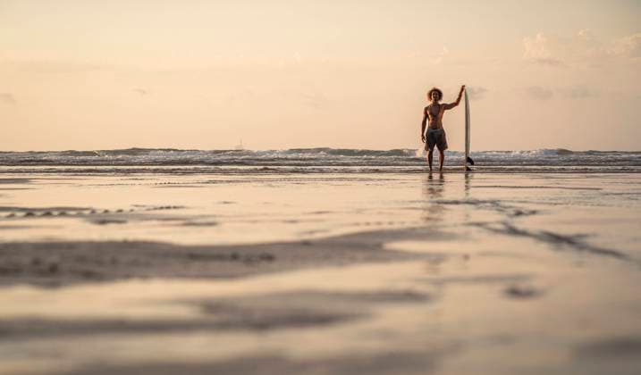 IMAGO Creative: Reflexionen - Sport Shirtless man standing with surfboard at seashore against sky during sunset model released Symbolfoto property released SNF00674