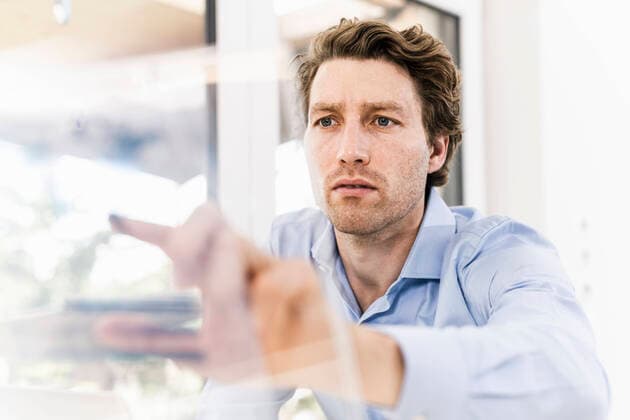 IMAGO Creative: Corporate: Klimaschutz, Digitalisierung und Urbanisierung Mid adult man pointing on glass material while sitting in office model released Symbolfoto property released UUF21891
