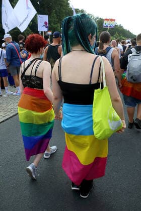 Berliner CHRISTOPHER STREET DAY 2021 - CSD - Am 24. Juli 2021 zieht der CSD in Berlin unter dem Motto SAVE OUR COMMUNITY SAVE YOUR PRIDE zum 43. Mal durch die Hauptstadt. Zwei Demoteilnehmerinnen in Regenbogenflaggen gehüllt. Die bunte CSD-Parade startete in diesem Jahr als Demonstration an der Leipziger Straße, führte über den Potsdamer Platz, vorbei am Denkmal für die im Nationalsozialismus verfolgten Homosexuellen zum Brandenburger Tor und über die Siegessäule zur Urania. Aufgrund der Corona-Pandemie fand die Demonstration ausschließlich unter Einhaltung der vom Berliner Senat erlassenen Vorgaben statt. Die in den Vorjahren übliche Abschlusskundgebung musste daher ausfallen.