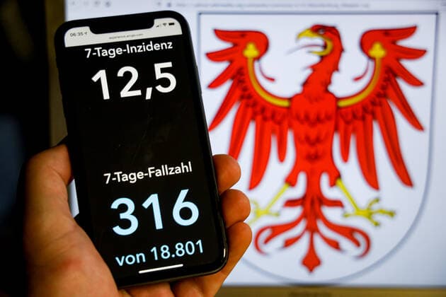 Coronavirus in Deutschland - Covid-19-Dashboard des Robert Koch-Institut DEU, Deutschland, Brandenburg, 08.08.2021: Die 7-Tage-Inzidenz für das Bundesland (Fälle letzte 7 Tage 100.000 EW) wird auf einem iPhone angezeigt, im Hintergrund das Landeswappen