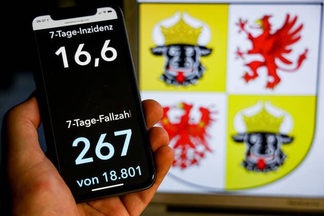 Coronavirus in Deutschland - Covid-19-Dashboard des Robert Koch-Institut DEU, Deutschland, Mecklenburg-Vorpommern, 08.08.2021: Die 7-Tage-Inzidenz für das Bundesland (Fälle letzte 7 Tage 100.000 EW) wird auf einem iPhone angezeigt, im Hintergrund das Landeswappen