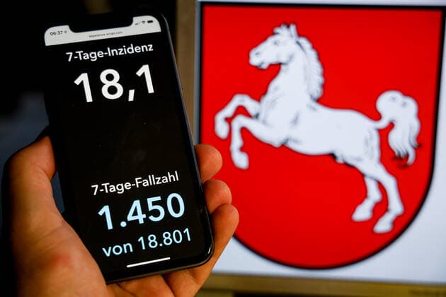 Coronavirus in Deutschland - Covid-19-Dashboard des Robert Koch-Institut DEU, Deutschland, Niedersachsen, 08.08.2021: Die 7-Tage-Inzidenz für das Bundesland (Fälle letzte 7 Tage 100.000 EW) wird auf einem iPhone angezeigt, im Hintergrund das Landeswappen