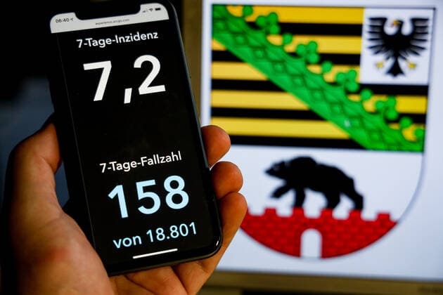 Coronavirus in Deutschland - Covid-19-Dashboard des Robert Koch-Institut DEU, Deutschland, Sachsen-Anhalt, 08.08.2021: Die 7-Tage-Inzidenz für das Bundesland (Fälle letzte 7 Tage 100.000 EW) wird auf einem iPhone angezeigt, im Hintergrund das Landeswappen