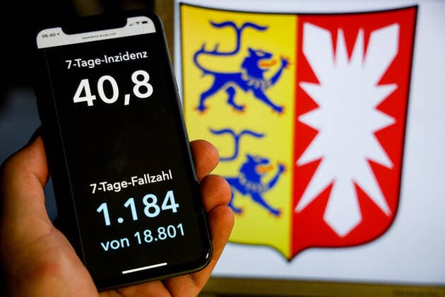 Coronavirus in Deutschland - Covid-19-Dashboard des Robert Koch-Institut DEU, Deutschland, Schleswig-Holstein, 08.08.2021: Die 7-Tage-Inzidenz für das Bundesland (Fälle letzte 7 Tage 100.000 EW) wird auf einem iPhone angezeigt, im Hintergrund das Landeswappen