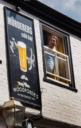 August 10, 2021, Norwich, United Kingdom: One of the guests at a private party looks out of the pub window during the demonstration..Anti vax-passport protesters visit Norwich to highlight the discrimination they believe is taking place at The Murderers pub. The landlord Phil Cutter has introduced a new no jab, no entry rule that he says protects both his staff and customers. Norwich United Kingdom - ZUMAs197 20210810_zaa_s197_301 Copyright: xMartinxPopex