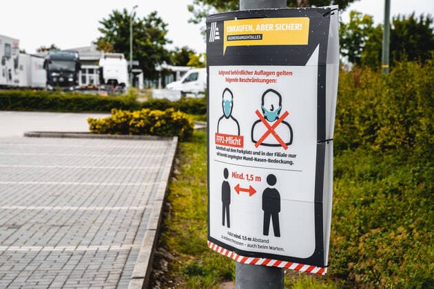 Hinweise zum Einhalten der FFP 2 Maskenpflicht und Einhaltung des Mindestabstand Covid 19 Coronavirus Schutzmaßnahmen auf dem Parkplatz eines Deutschen Aldi Süd Lebensmittel Geschäftes