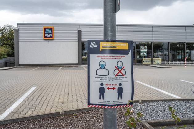 Hinweise zum Einhalten der FFP 2 Maskenpflicht und Einhaltung des Mindestabstand Covid 19 Coronavirus Schutzmaßnahmen auf dem Parkplatz eines Deutschen Aldi Süd Lebensmittel Geschäftes
