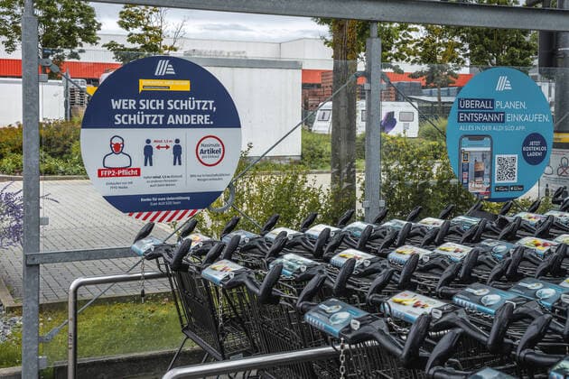 Hinweise zum Einhalten der FFP 2 Maskenpflicht und Einhaltung des Mindestabstand Covid 19 Coronavirus Schutzmaßnahmen auf dem Parkplatz eines Deutschen Aldi Süd Lebensmittel Geschäftes