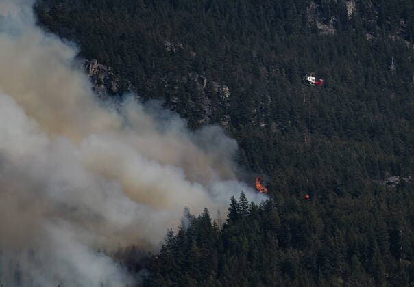 August 15, 2021, LYTTON, BC, CANADA: A helicopter carrying a water bucket flies past the Lytton Creek wildfire burning in the mountains near Lytton, B.C., on Sunday, August 15, 2021. LYTTON CANADA  - ZUMAc35_ 20210815_zaf_c35_089 Copyright: xDarrylxDyckx