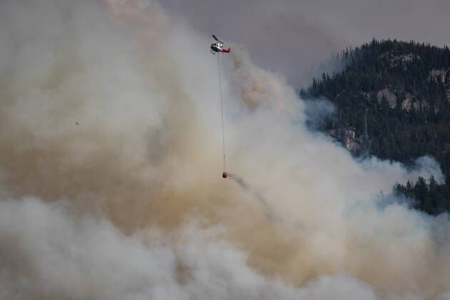 August 15, 2021, LYTTON, BC, CANADA: A helicopter carrying a water bucket flies past the Lytton Creek wildfire burning in the mountains near Lytton, B.C., on Sunday, August 15, 2021. LYTTON CANADA  - ZUMAc35_ 20210815_zaf_c35_102 Copyright: xDarrylxDyckx